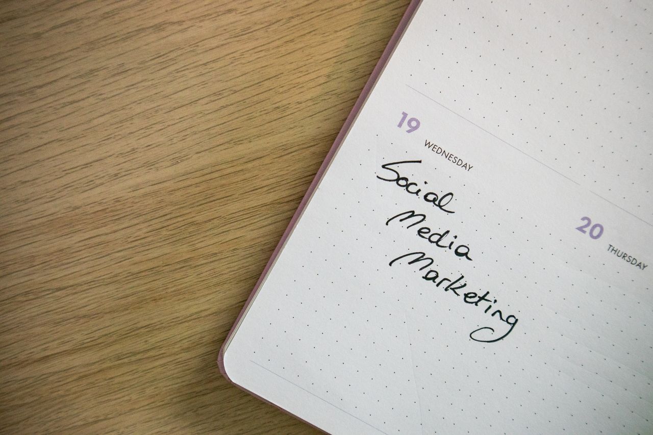 Close-up view of a notebook page with Social Media Marketing written by hand on it.